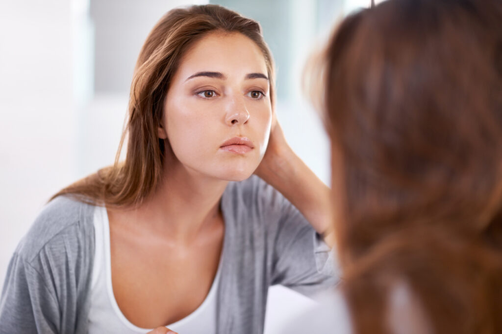 Girl looking through a mirror at her skin